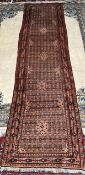 A red ground runner with multiple medallions, stylised flowers and guard stripes,