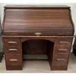 A 20th century oak roll top desk with a serpentine tambour front enclosing a fitted interior of