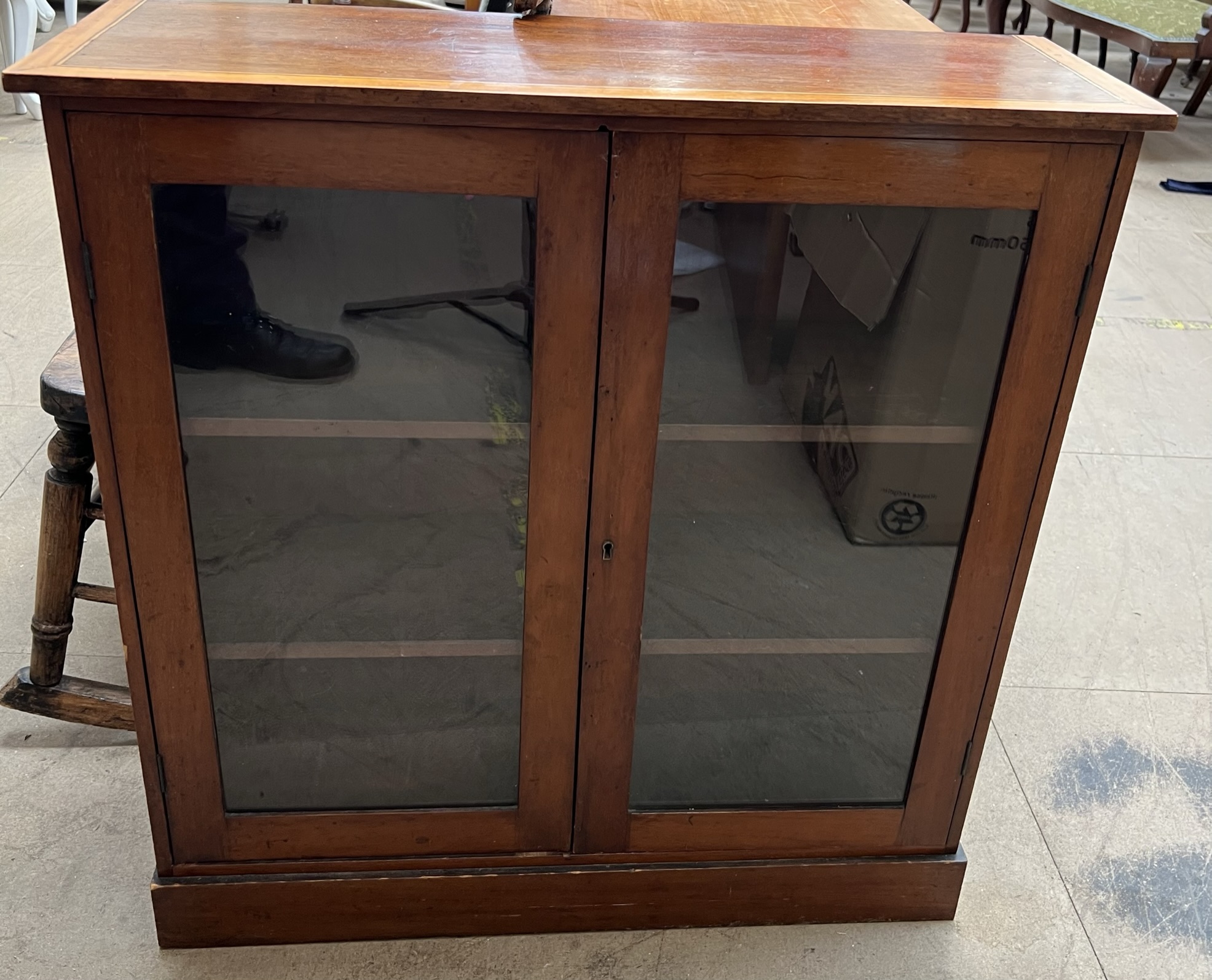 An Edwardian mahogany bookcase with a moulded top above a pair of glazed doors on a plinth base