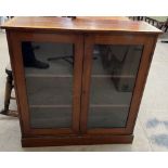 An Edwardian mahogany bookcase with a moulded top above a pair of glazed doors on a plinth base