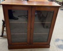 An Edwardian mahogany bookcase with a moulded top above a pair of glazed doors on a plinth base