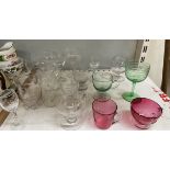 Two cranberry glass mugs together with green glass drinking glasses and other glasswares ***PLEASE