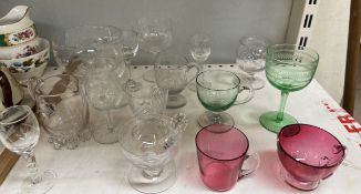 Two cranberry glass mugs together with green glass drinking glasses and other glasswares ***PLEASE