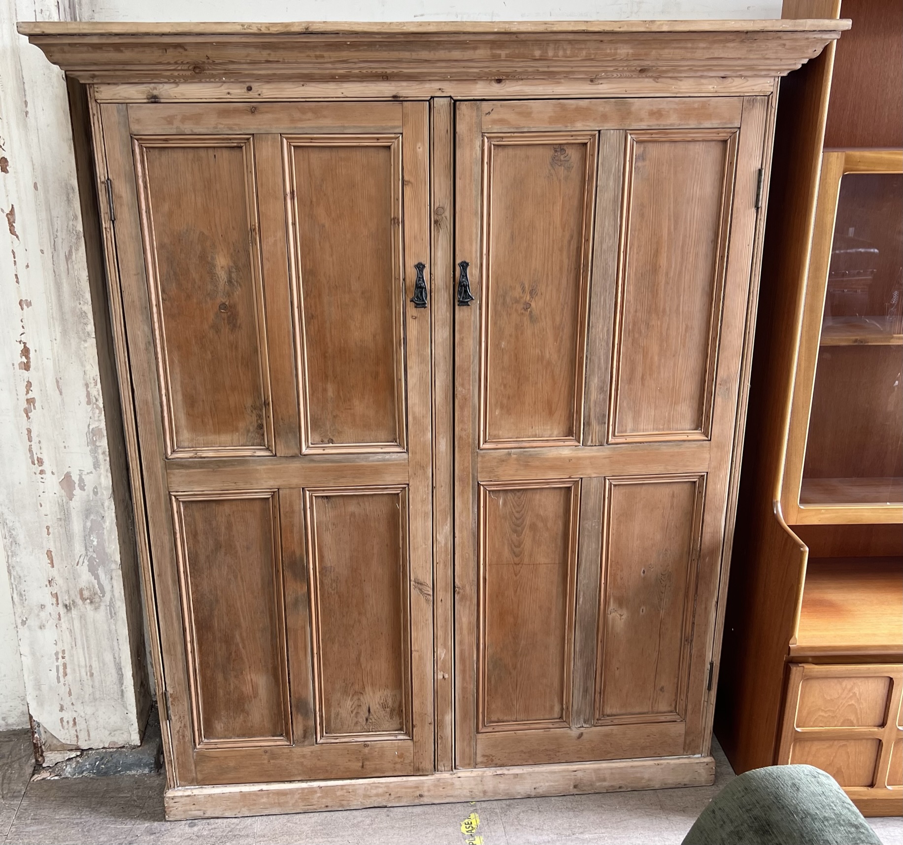 A large pine side cabinet with a moulded cornice above a pair of panelled cupboard doors on a