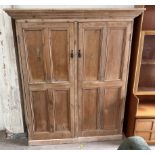 A large pine side cabinet with a moulded cornice above a pair of panelled cupboard doors on a
