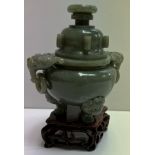 A Chinese green hardstone / jade vase and cover with lion and ring handles on three feet and a base