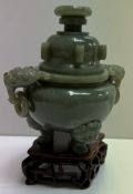 A Chinese green hardstone / jade vase and cover with lion and ring handles on three feet and a base