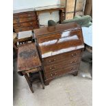 An Edwardian mahogany bureau with a sloping fall and three long drawers on bracket feet together