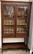 An Edwardian mahogany display cabinet with a moulded cornice and shallow swag decorated frieze with