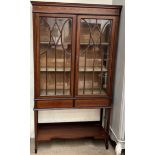 An Edwardian mahogany display cabinet with a moulded cornice and shallow swag decorated frieze with