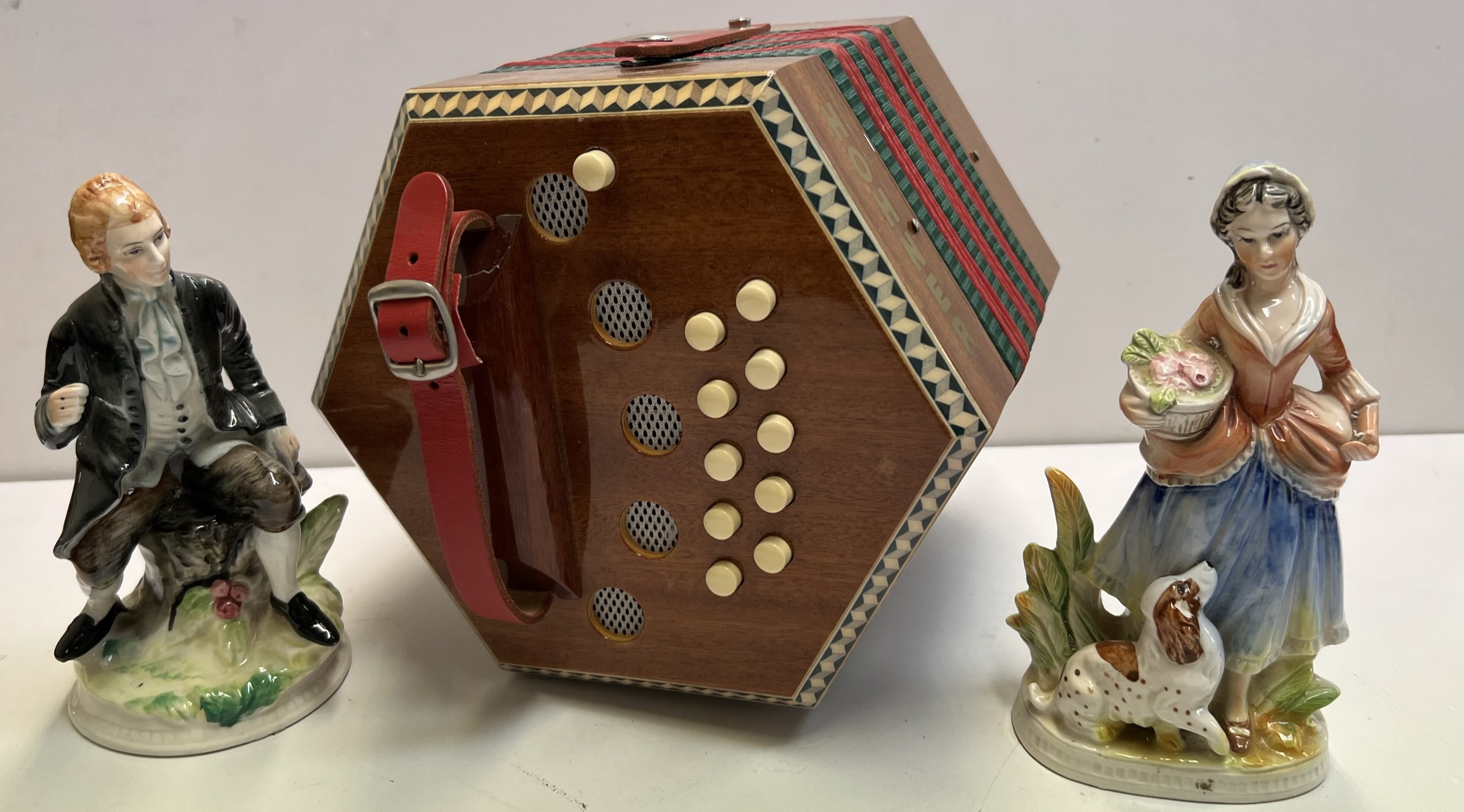 A Hohner concertina together with a pair of continental pottery figures