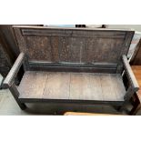 An 18th century oak settle, with a three panel back and planked seat on square legs,