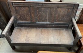 An 18th century oak settle, with a three panel back and planked seat on square legs,