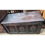 An 18th century carved oak coffer with a three panelled front on stiles