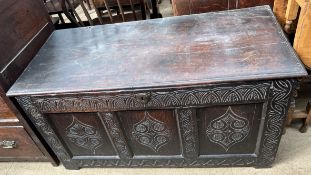 An 18th century carved oak coffer with a three panelled front on stiles