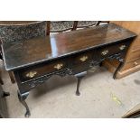An early 20th century oak dresser base with three drawers and a pierced rail on cabriole legs and