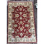 A Pakistan woollen rug with a red ground and interlaced flowers and a yellow border,