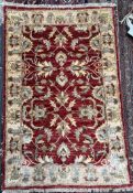 A Pakistan woollen rug with a red ground and interlaced flowers and a yellow border,