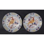 A pair of 18th century delftware pancake plates polychrome decorated with a bird perched on a