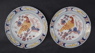 A pair of 18th century delftware pancake plates polychrome decorated with a bird perched on a