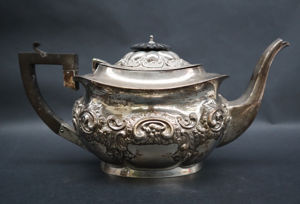An Edward VII silver teapot of oval form embossed with flowers, leaves and scrolls, Birmingham,