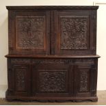 An 18th century oak side cabinet with a carved cornice above a pair of carved doors,