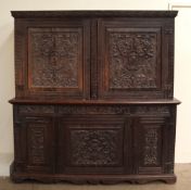 An 18th century oak side cabinet with a carved cornice above a pair of carved doors,