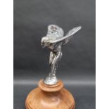 A chrome plated Spirit of Ecstacy car mascot, mounted on a turned wooden base,