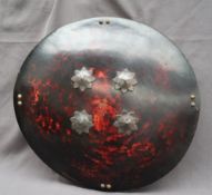 A mock tortoiseshell shield, of circular form, with applied metal buttons and flowers, 57.