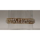 A yellow metal pearl set bangle, with two rows of irregular pearls,