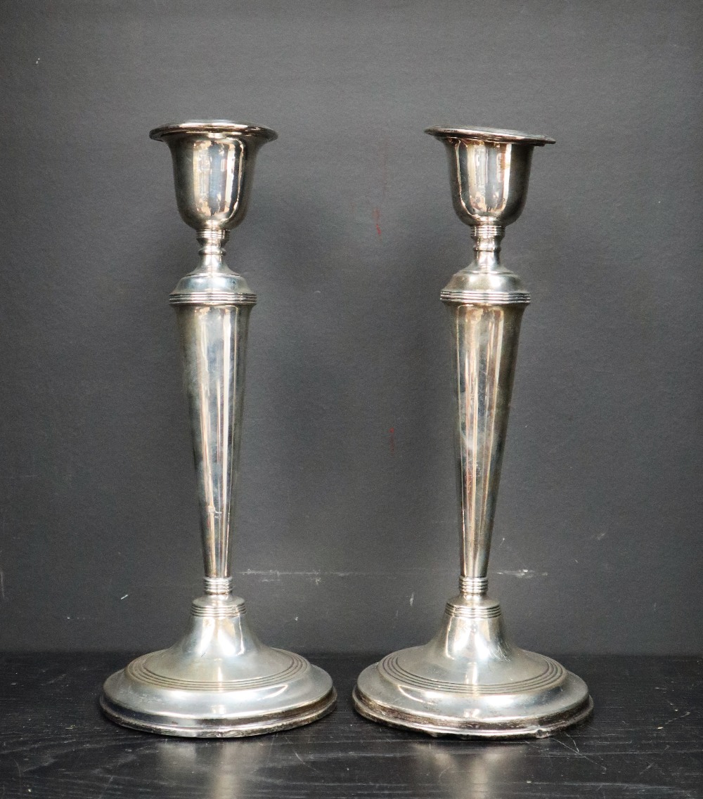 A pair of George VI silver candlesticks, with a shaped sconce and tapering body on spreading foot,