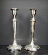 A pair of George VI silver candlesticks, with a shaped sconce and tapering body on spreading foot,