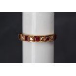 A ruby and diamond half eternity ring set with five princess cut rubies and four round brilliant