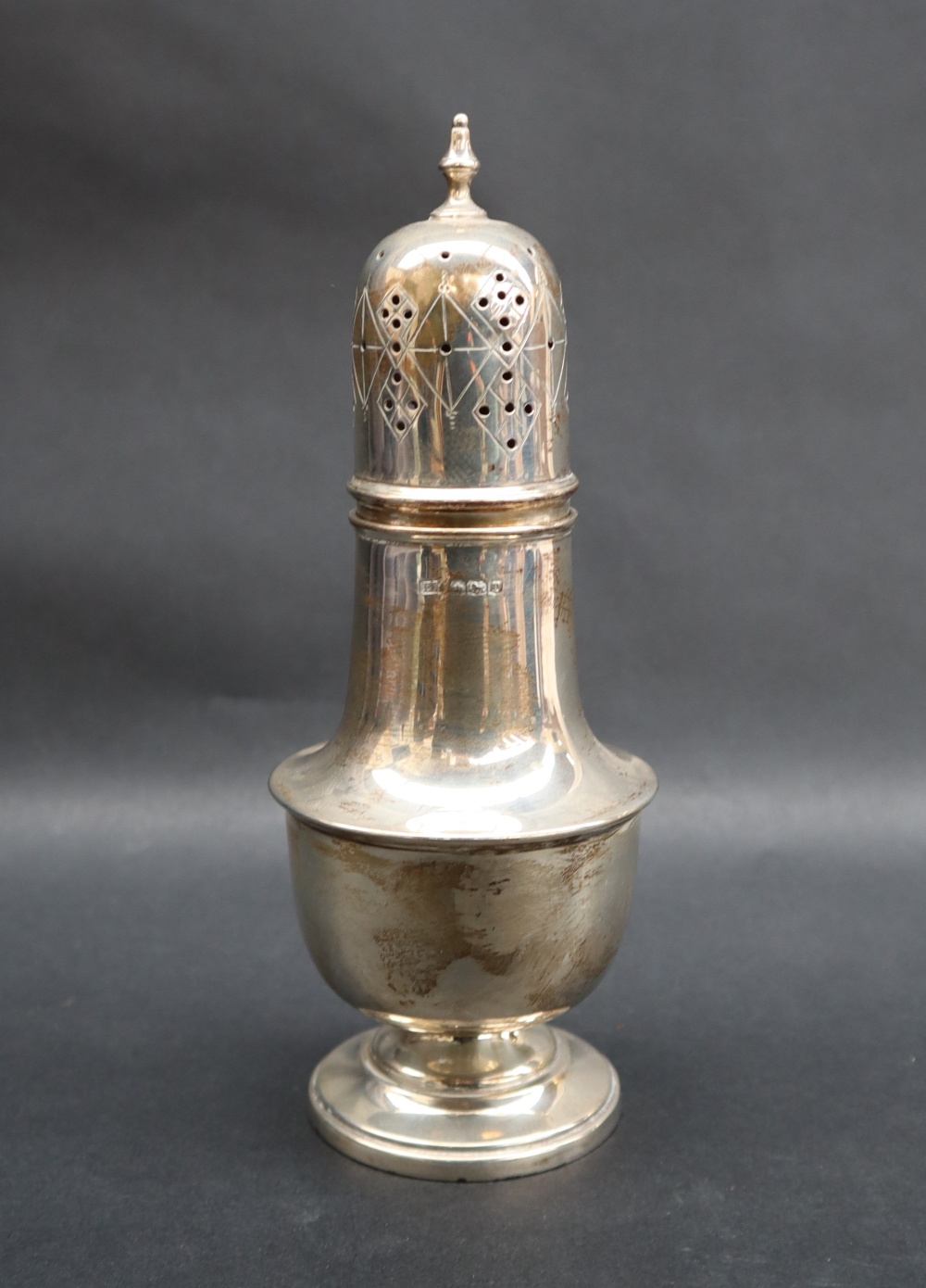 A George V silver sugar caster with a turned finial and a domed cover with a ring turned baluster