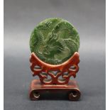 A Chinese carved jade disc depicting a dragon chasing a pearl, 6cm diameter,