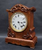 A Victorian walnut cased mantle clock, with an arched top, applied with scrolls and leaves,