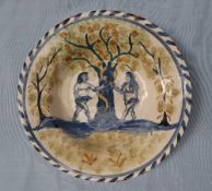 A tin glazed earthenware bowl with blue dash border decorated with Adam and Eve in the garden of