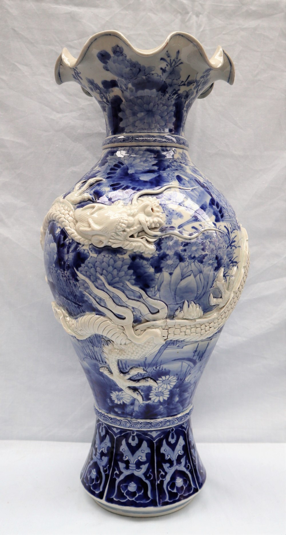 A Japanese blue and white porcelain vase decorated with a raised dragon encircling the vase further