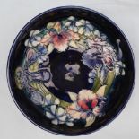 A Moorcroft pottery bowl decorated in the Orchid pattern to a Royal Blue Ground, 27cm diameter,