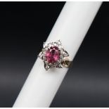 A ruby and diamond cluster ring, the central oval faceted ruby,