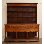 An 18th century oak dresser, the moulded cornice above three shelves,
