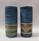 A pair of troika pottery vases of cylindrical form decorated with a band of green discs and lines,