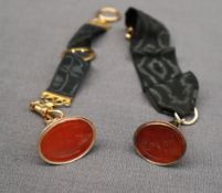 A yellow metal and hardstone fob seal engraved with a coat of arms on a 9ct gold mounted silk fob