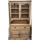 A Victorian pine dresser with a moulded cornice above a pair of glazed doors and shelves,
