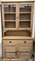 A Victorian pine dresser with a moulded cornice above a pair of glazed doors and shelves,