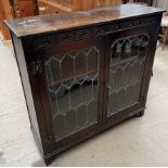 A 20th century oak bookcase with a rectangular top above a pair of leaded glazed doors on bracket