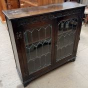 A 20th century oak bookcase with a rectangular top above a pair of leaded glazed doors on bracket