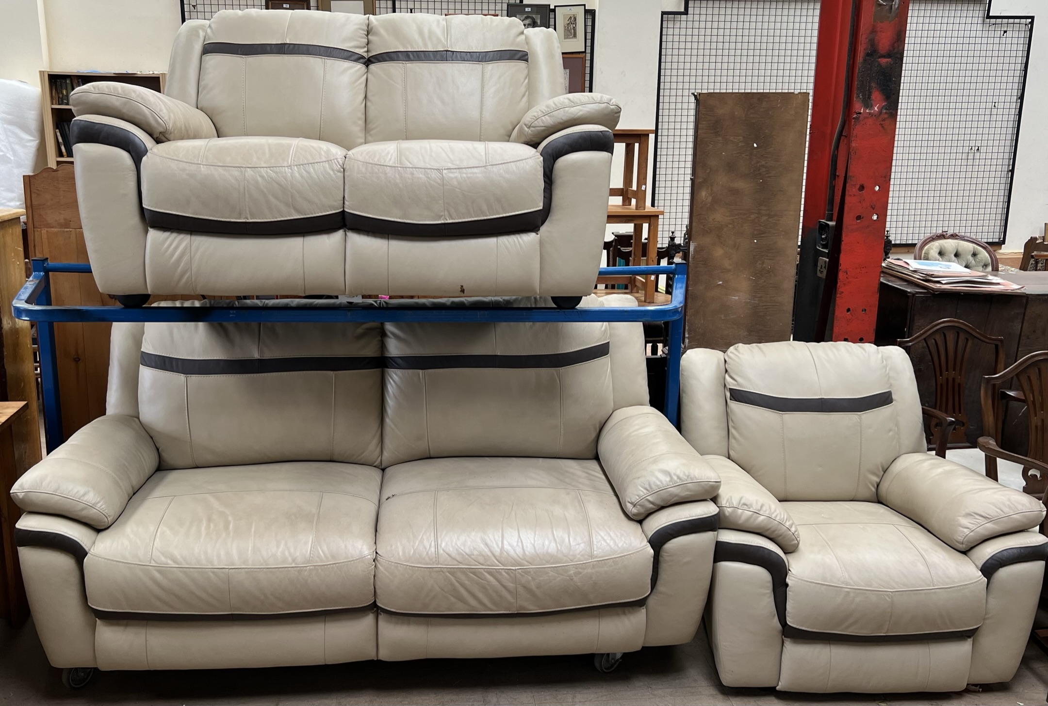 A cream and brown leather three piece suite comprising a three seater settee,