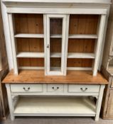 A modern painted pine kitchen dresser with a moulded cornice, shelves and central glazed door,