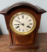 An Edwardian mahogany mantle clock with a domed top and pillars on brass ball feet with an